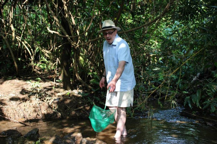 Professor George Turner standing in the river with a fishing net 