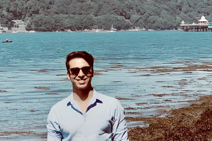 Dr Waleed Idrees smiling to camera in front of Bangor Pier that appears in the background.