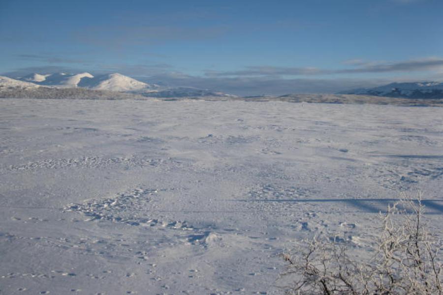 A frozen lake with mountains in background