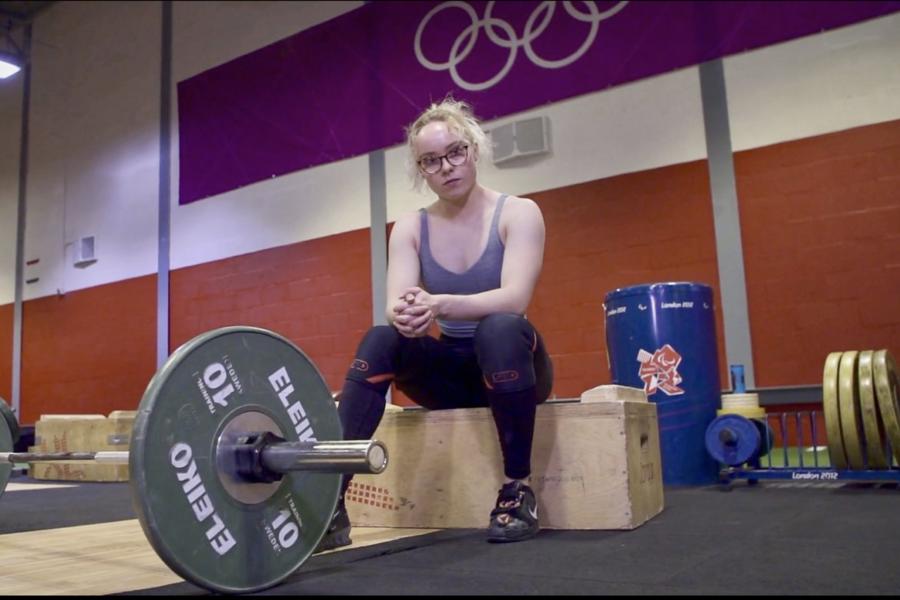 Athlete sat looking at the camera with weights on the bar