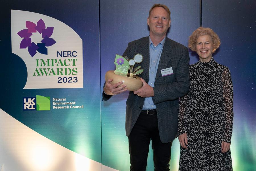 Image of Professor Davey Jones holding the NERC Impact Award trophy with Professor Louise Heathwaite 