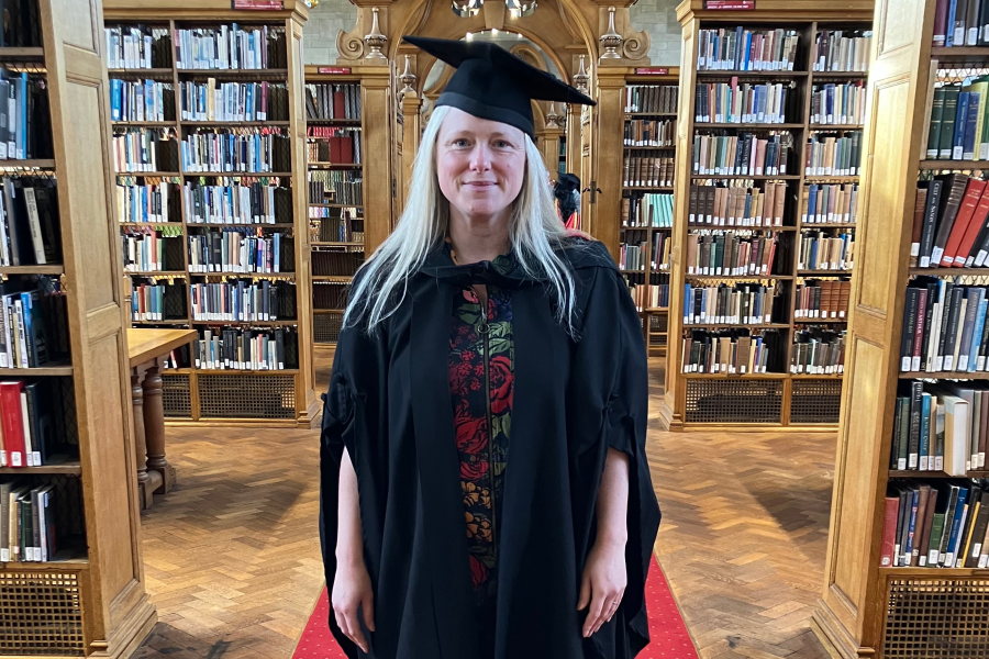 Person in an academic library in cap and gown