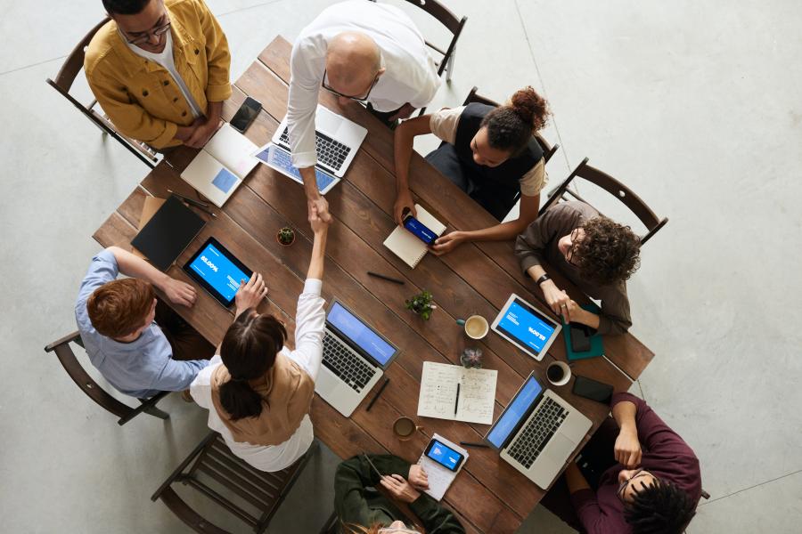 A group around a table with laptops and phones 