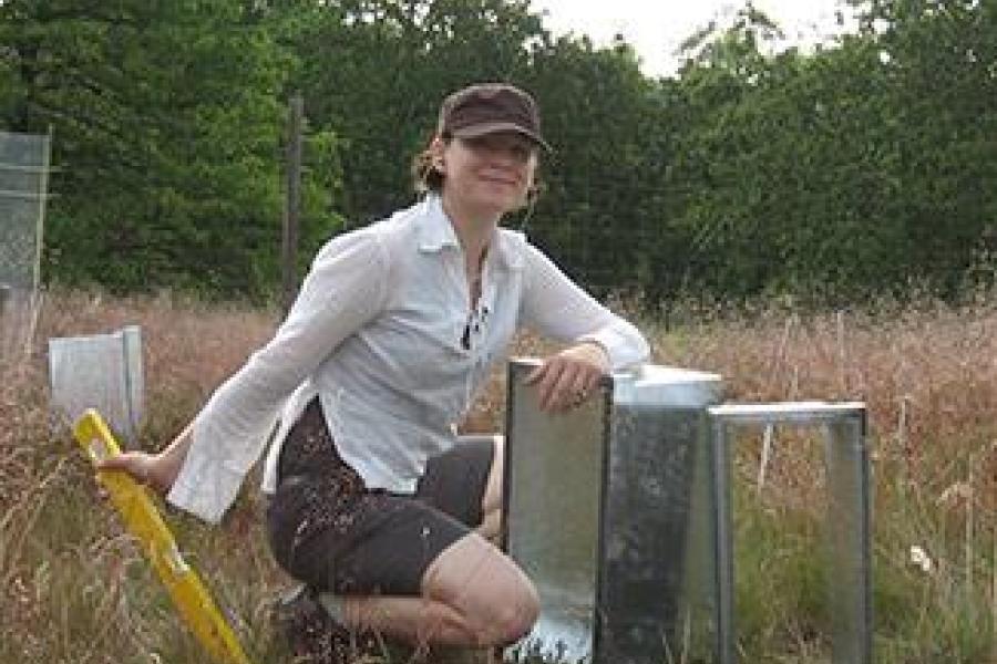 Sabine Reinsch conducting fieldwork, kneeling next to metal boxes, holding a spirit level