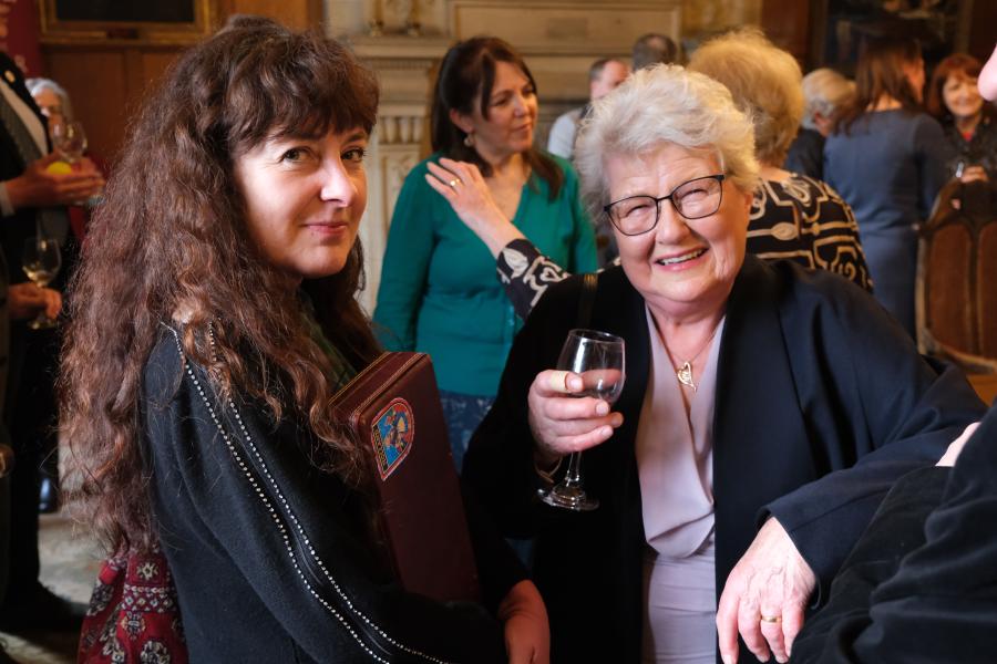 Gwesteion yn gwenu yn y camera yn ystod derbyniad alumni