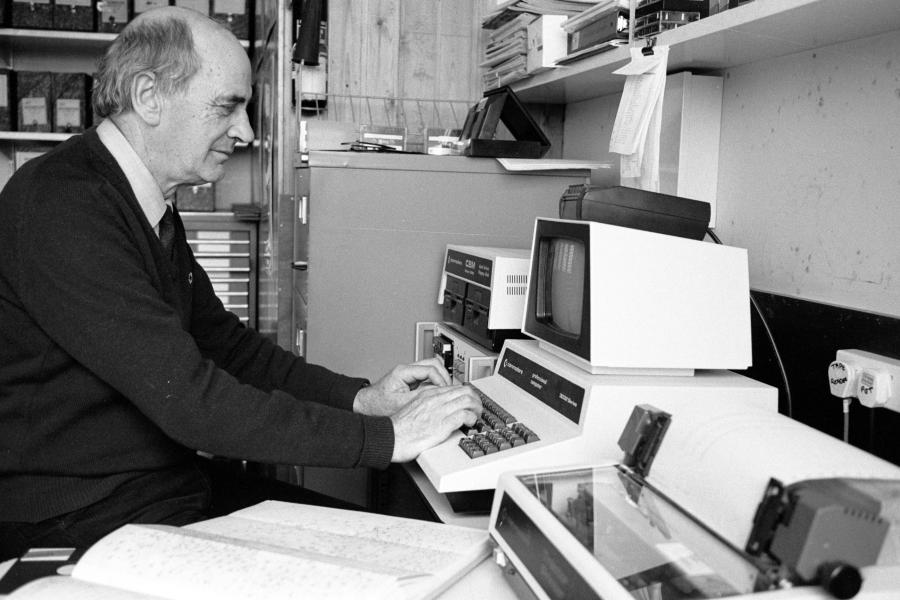black and white profile image of man sitting at old computer