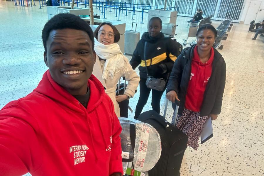 Student Support Staff at the airport with three students with suitcases in an airport