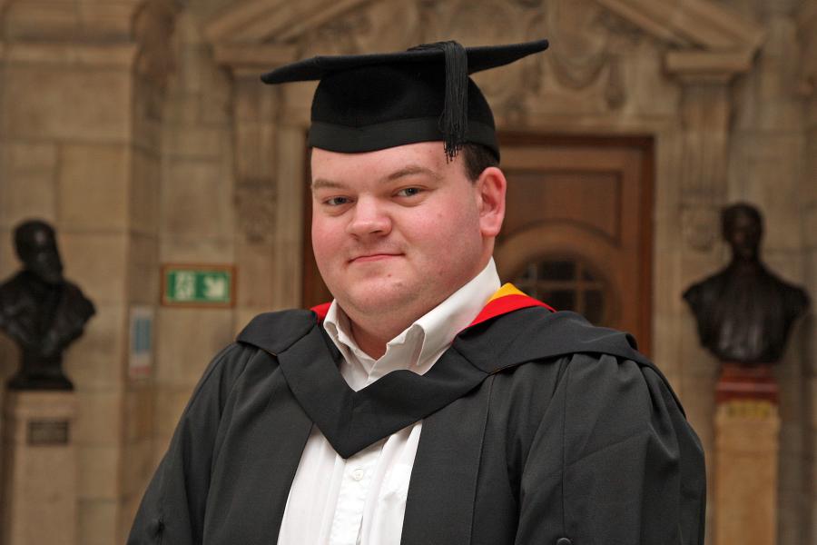 dyn ifanc mewn gwisg graddio