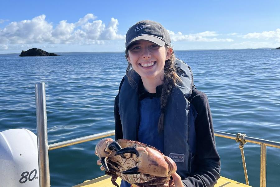 Researcher Emily Philips on a boat holding a large crab