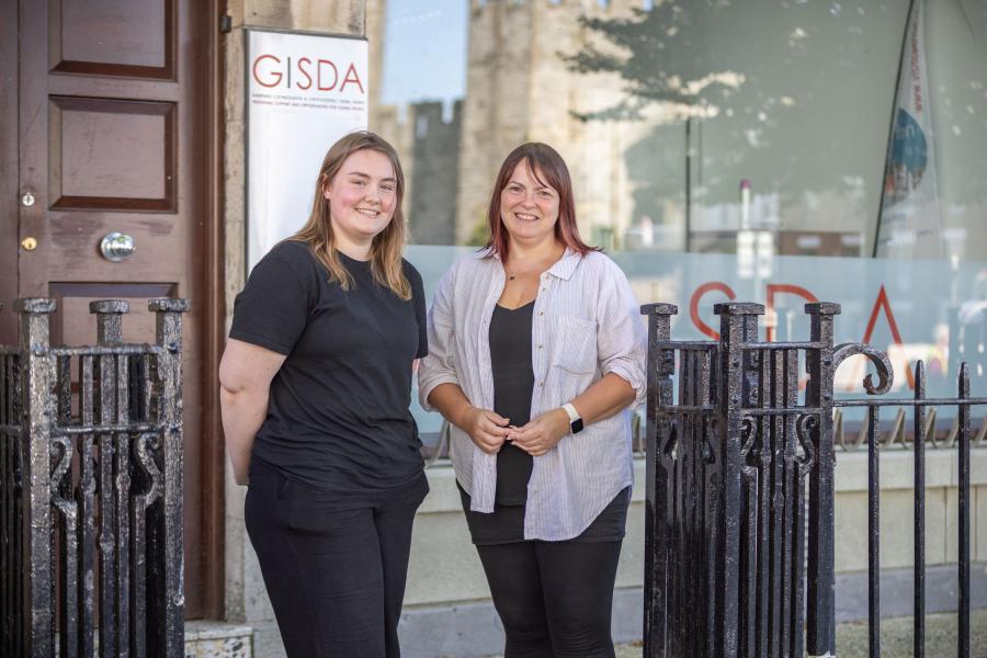 Two women smiling at camera with GISDA banner behind them