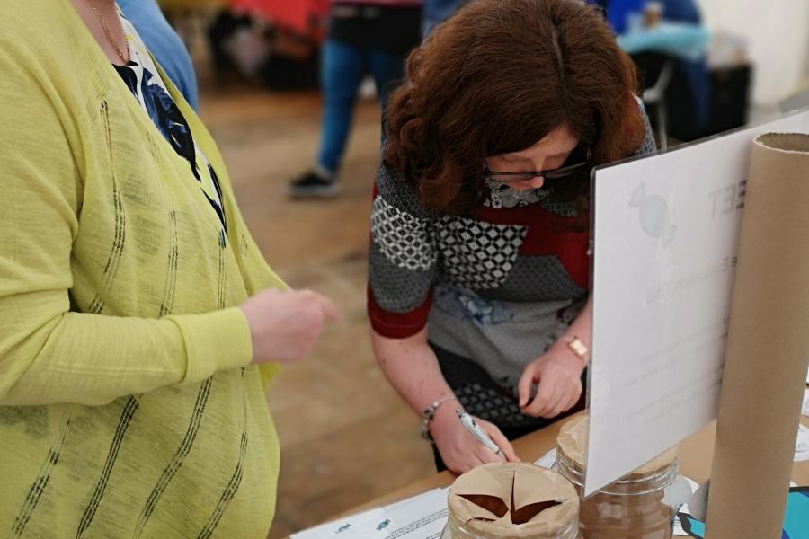 Woman talking to woman in front of stall at research event