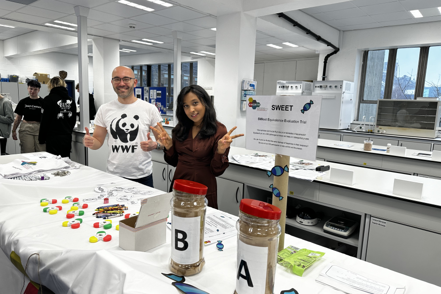 Man and woman standing smiling behind a stall at a research event