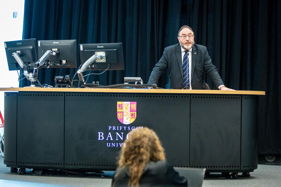 Image of Professor Edmund Burke giving a talk, standing behind a desk