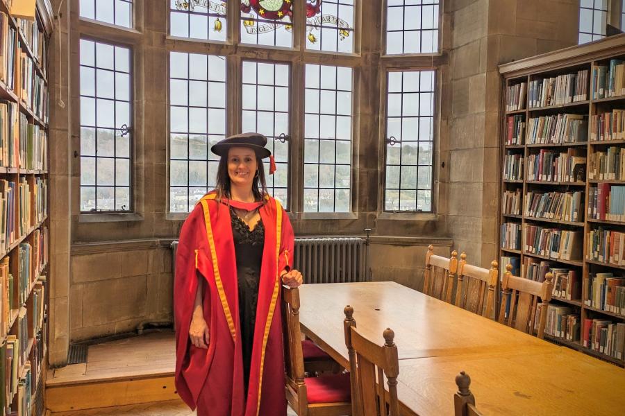 Dr Simone Calabrich in the Bangor University library on graduation day in red gown