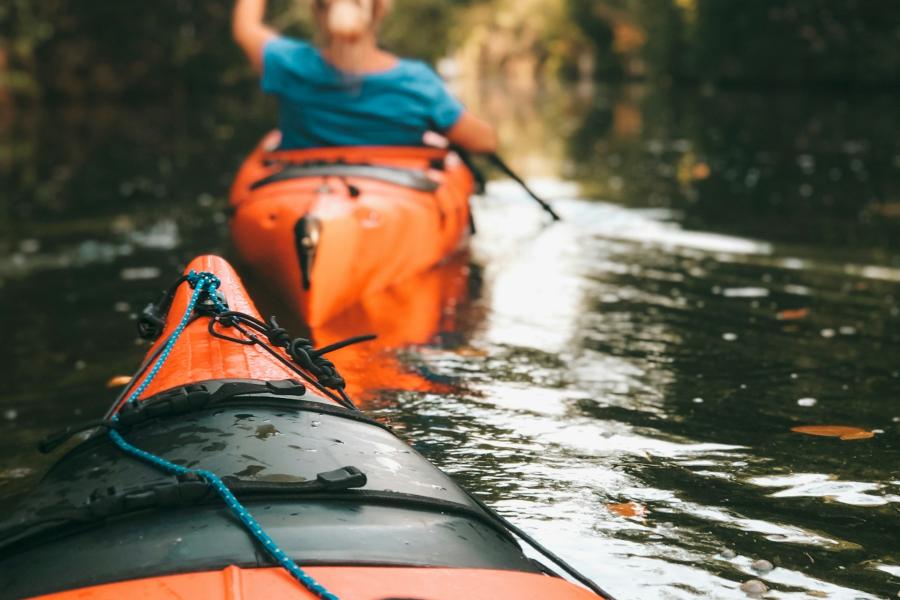 orange kayaks on a river, person paddling
