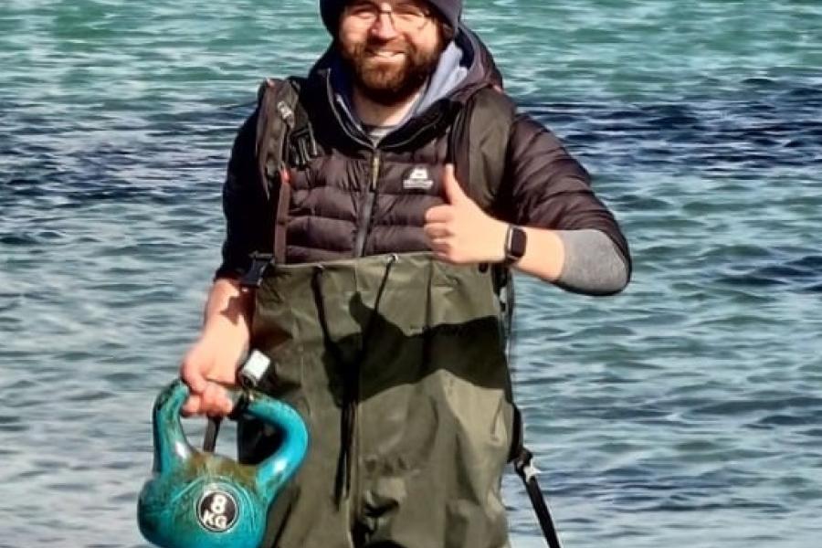 Dr James Waggit knee deep in the Irish sea, thumbs up and holding a research mooring.