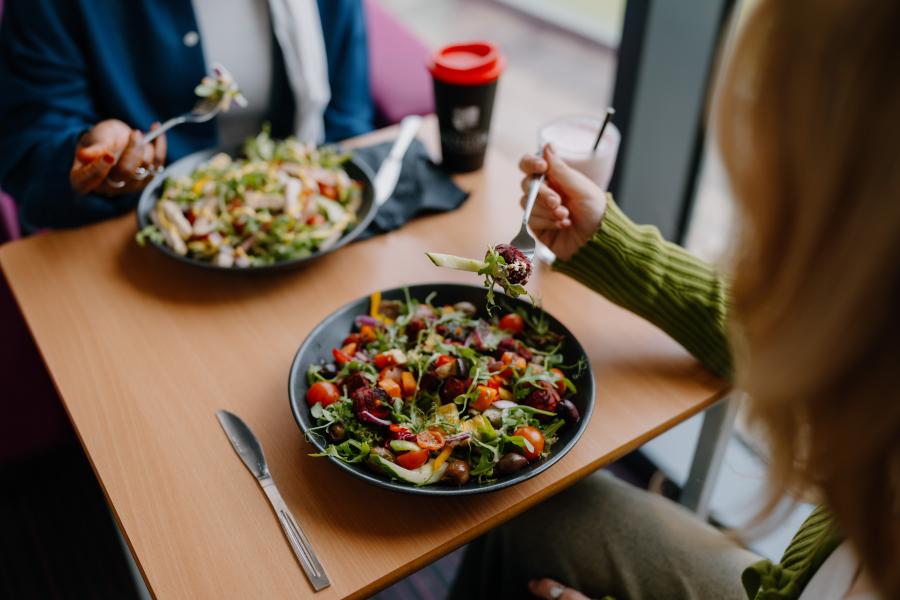 Two bowls of vibrant salad served in black bowls on a wooden table in Cegin, Pontio