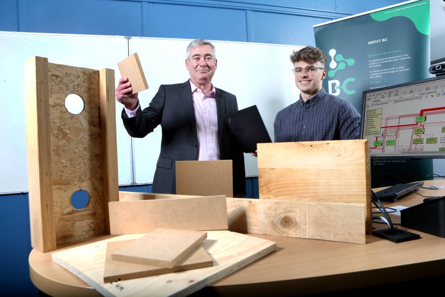 George and Campbell behind a desk of timber and next to a computer screen
