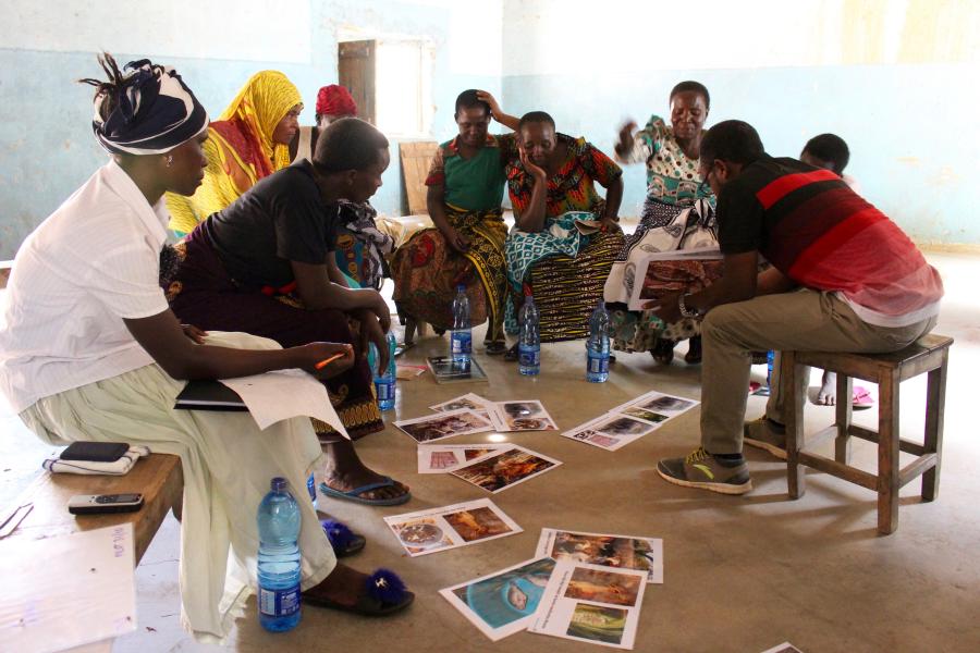 Photo of a dozen people sat around discussing a collection of images on the floor