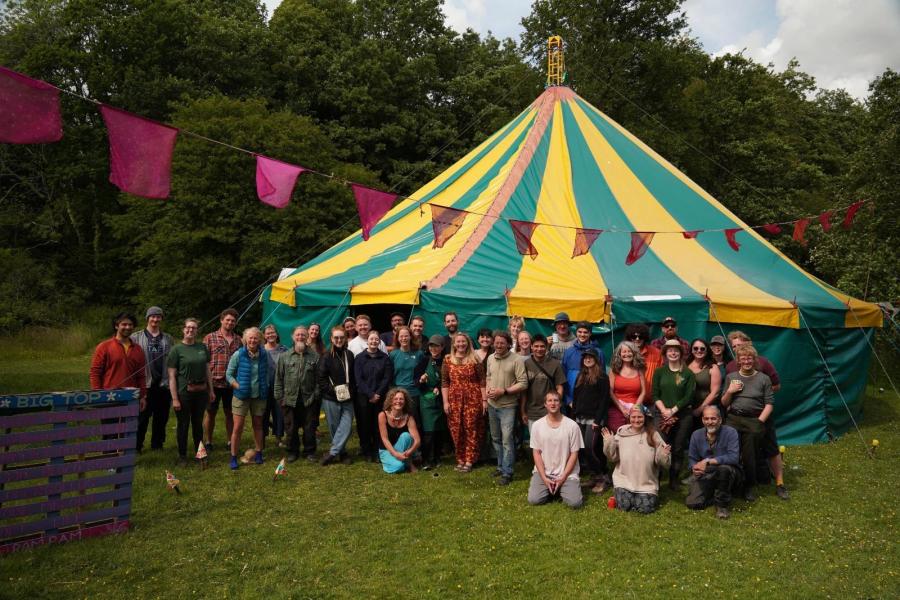 People standing in front of a green and yellow marquee in a field