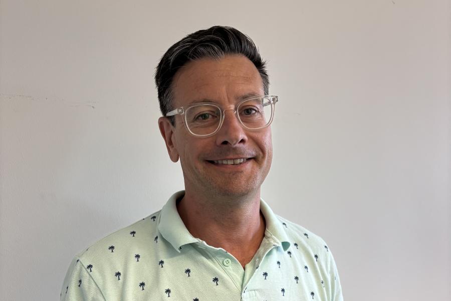Professor James Hardy wearing a pale green short sleeved shirt and glasses looking to camera.