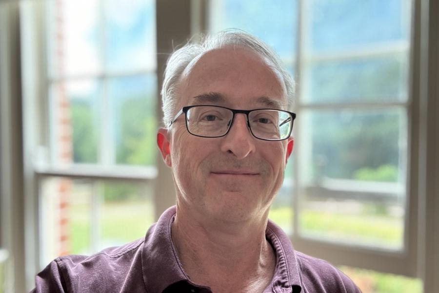 Prof Paul Downing looking to camera wearing glasses and a burgundy top