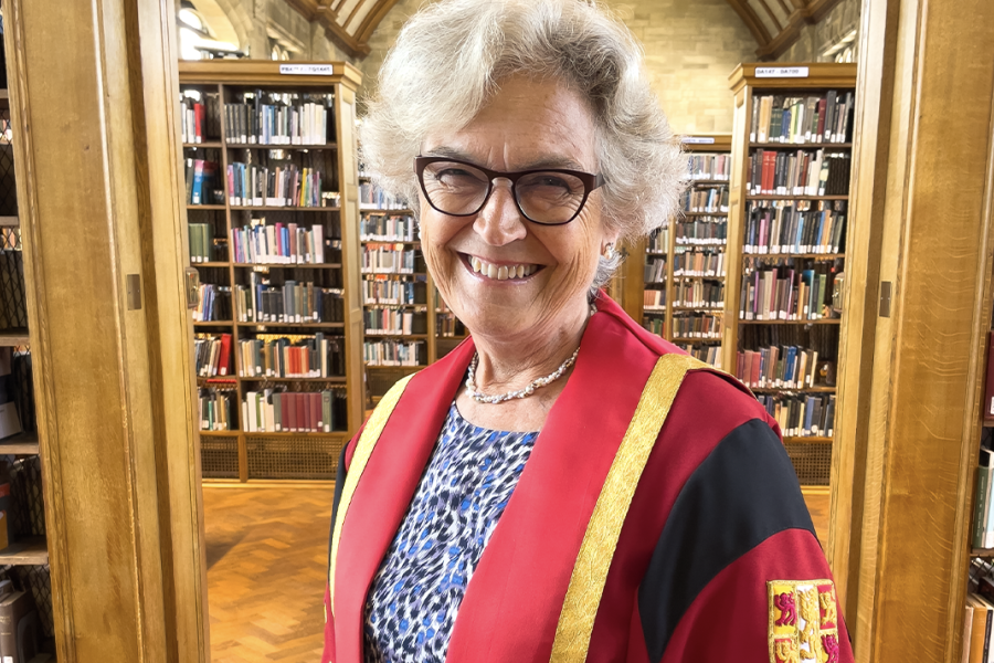 Image of Alison Field wearing a red and gold graduation robe