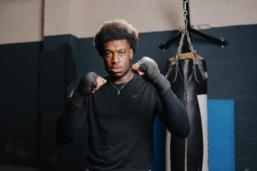 A student is stood facing the camera with his hands up in a boxing stance