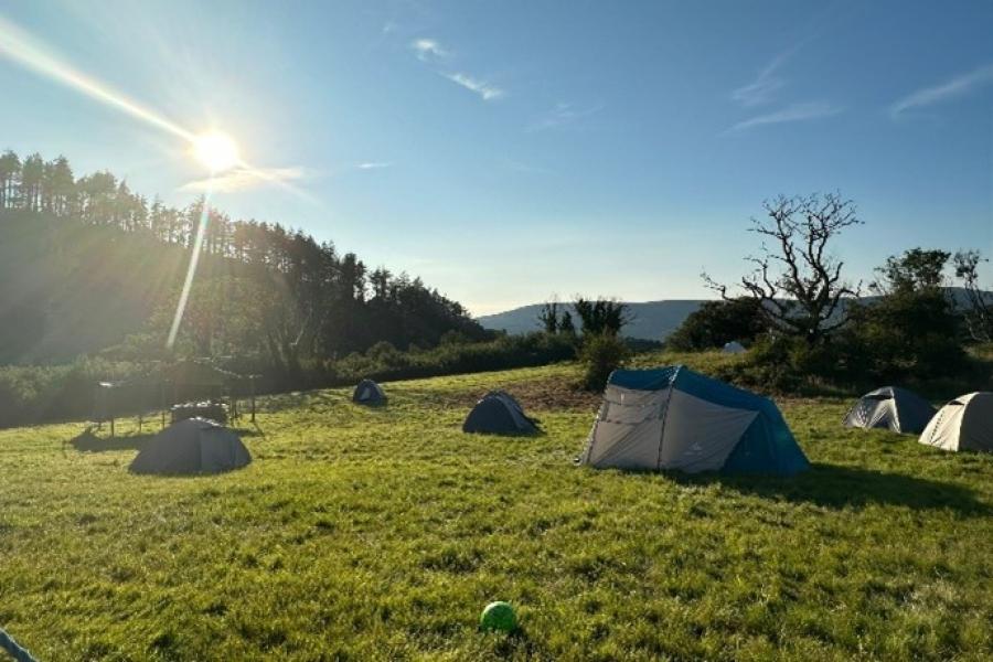 Image of a field and a blue sunny sky with tents pitched 