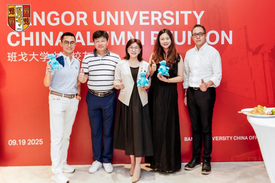 Alumni posing in front of reunion banner
