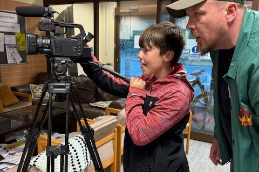 Young person being mentored to use a film camera