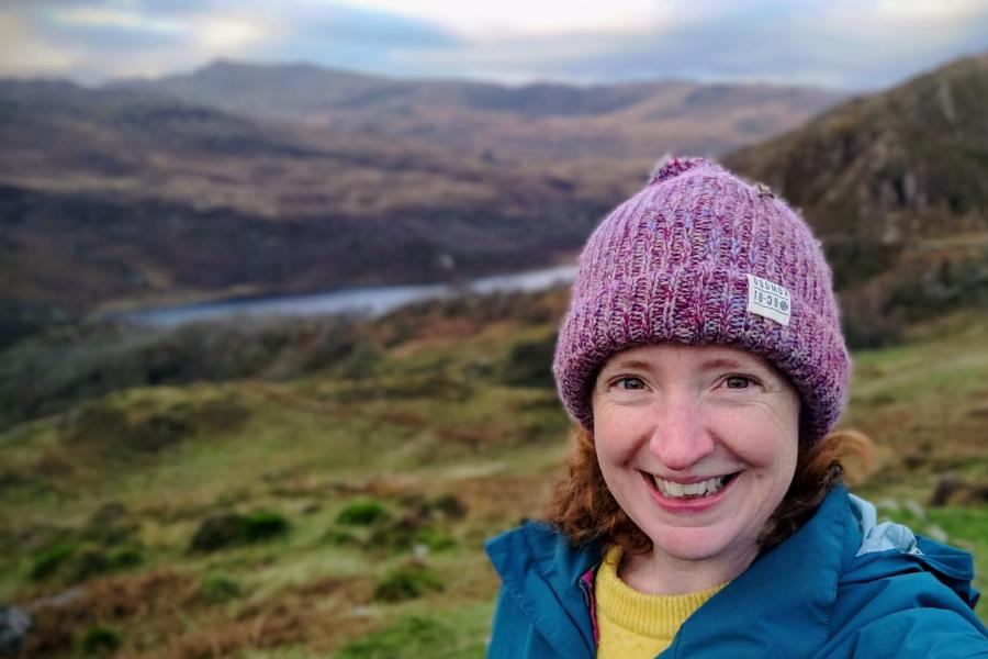 Green landscape with woman wearing a wooly hat 