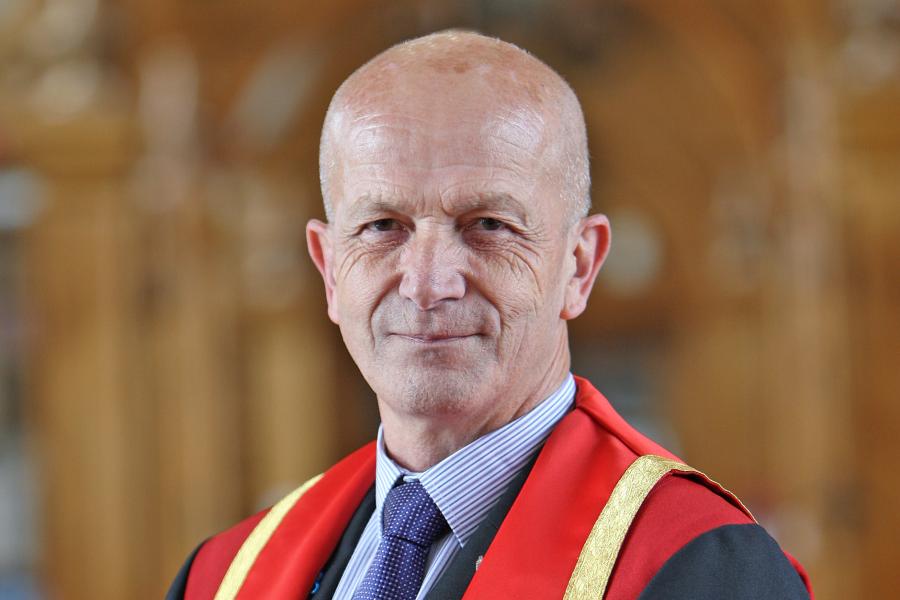 Llun proffil o Chris Roberts mewn gwisg graddio goch