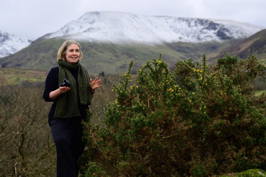 Julia yn addysgu gyda mynyddoedd Eryri dan eira yn y cefndir