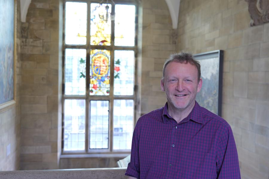 Andrew Webb standing in front of a stained window in Main Arts