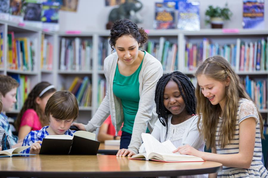 Children reading books with a teacher