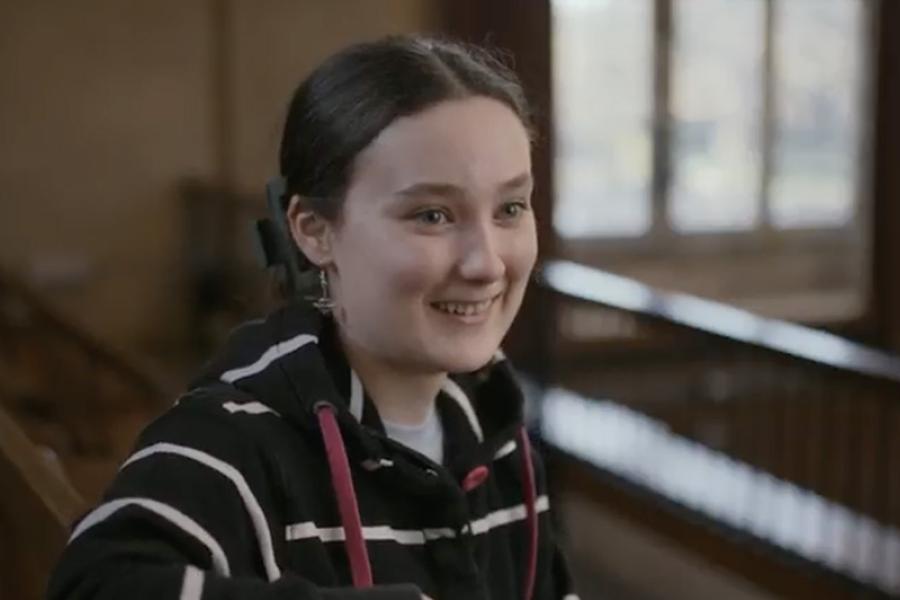 An image of Charlotte smiling to someone off camera in a large lecture theatre