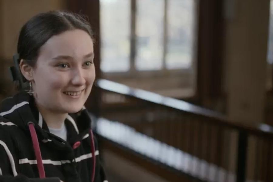 An image of Charlotte smiling to someone off camera in a large lecture theatre