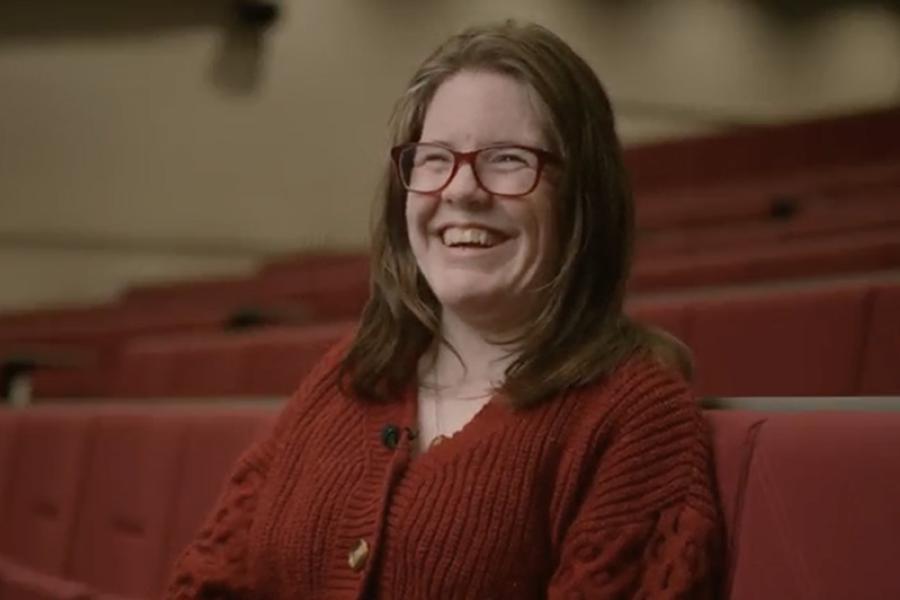 An image of Llywela smiling to camera in a large lecture theatre