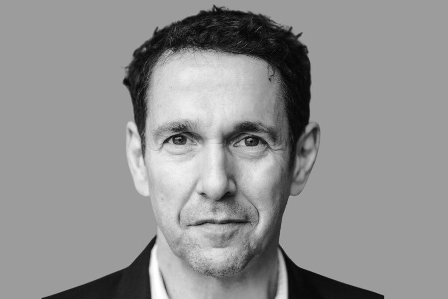 Black-and-white head-and-shoulders portrait of a person wearing a dark jacket