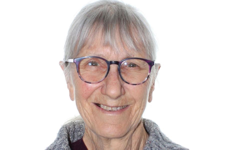 Head-and-shoulders portrait of a person with short grey hair and glasses, facing the camera against a white background