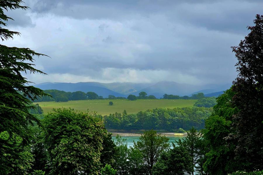 A photo showing, fields, trees and mountains over the Menai Strait