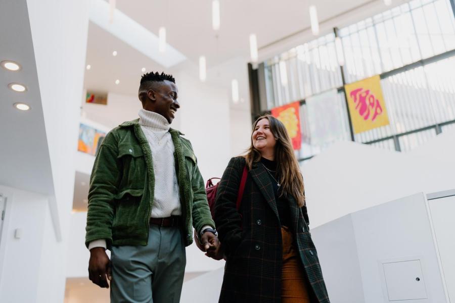 Two students walking and chatting in Pontio