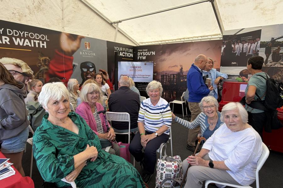 Alumni yn yr aduniad yn gwenu at y camera