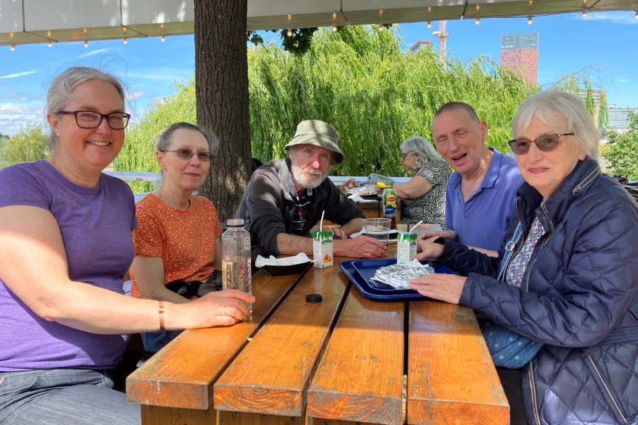 Alumni around a table in the sunshine