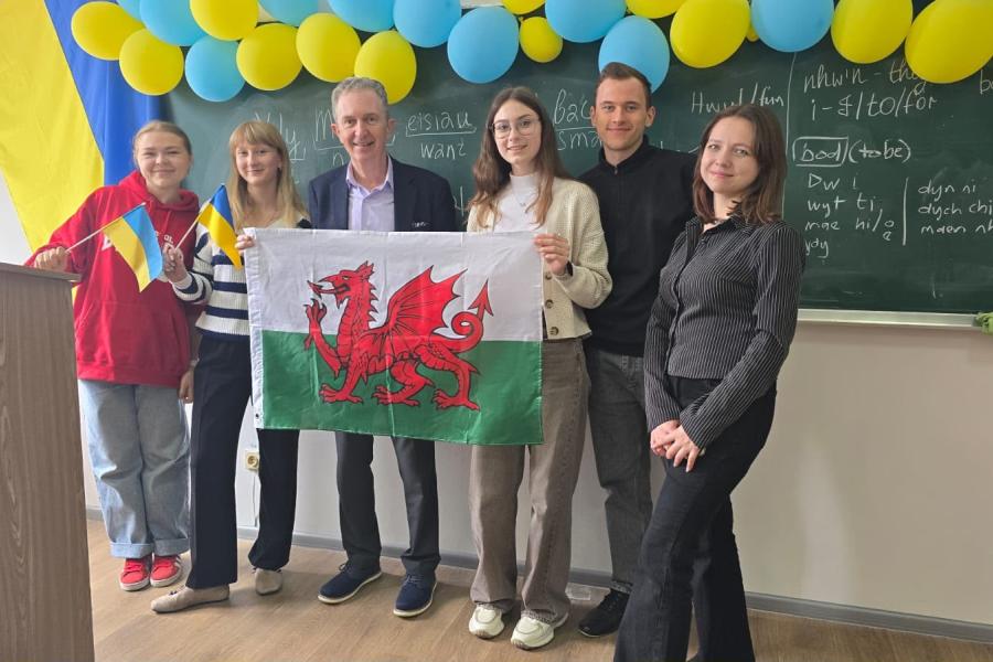 A group of people standing with a Welsh flag 