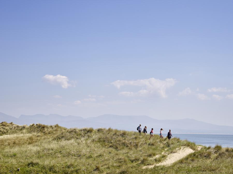 A group of students walking along the beach with the mountains in the background
