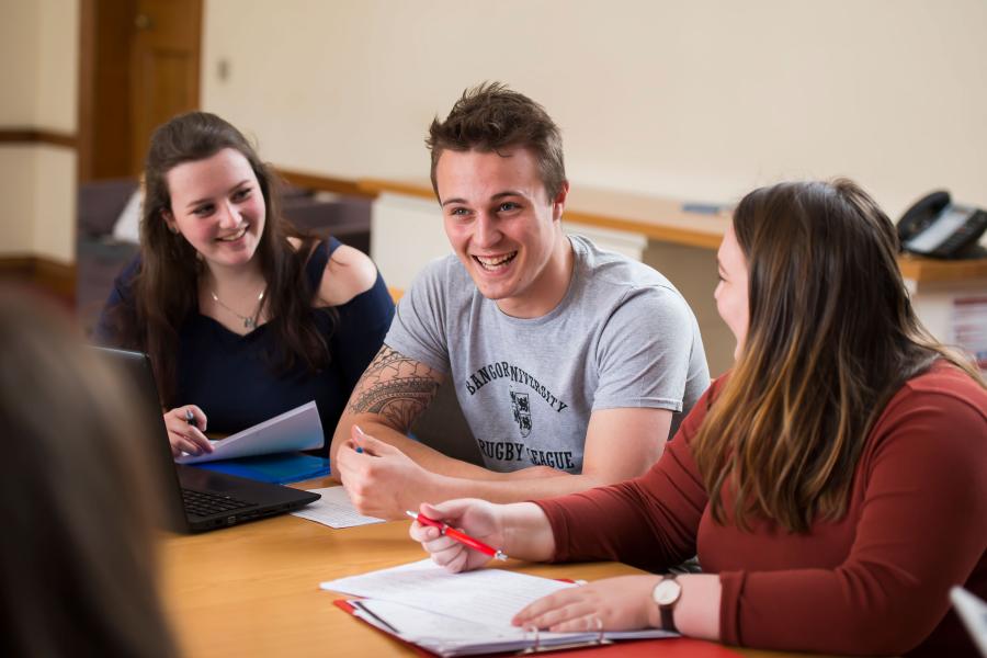 Myfyrwyr yn rhanny jôc yn ystod seminar