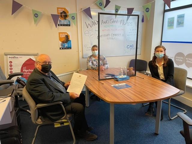 three masked people sit around a table