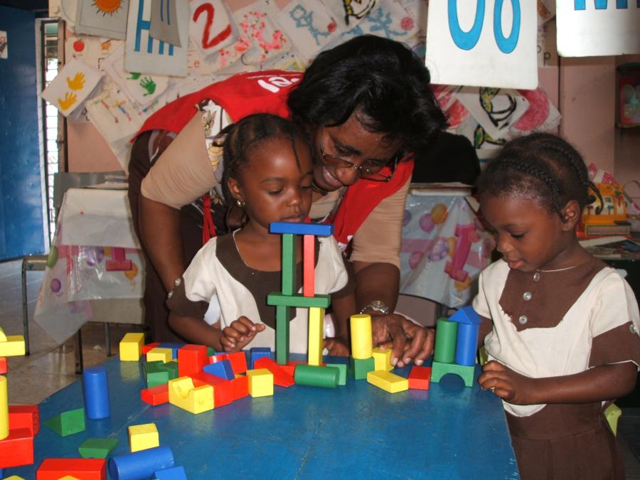 A teacher helping two children with building blocks